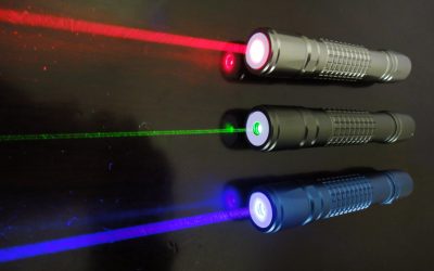 Three laser pointers on a dark surface emitting red, green, and blue laser beams, respectively.